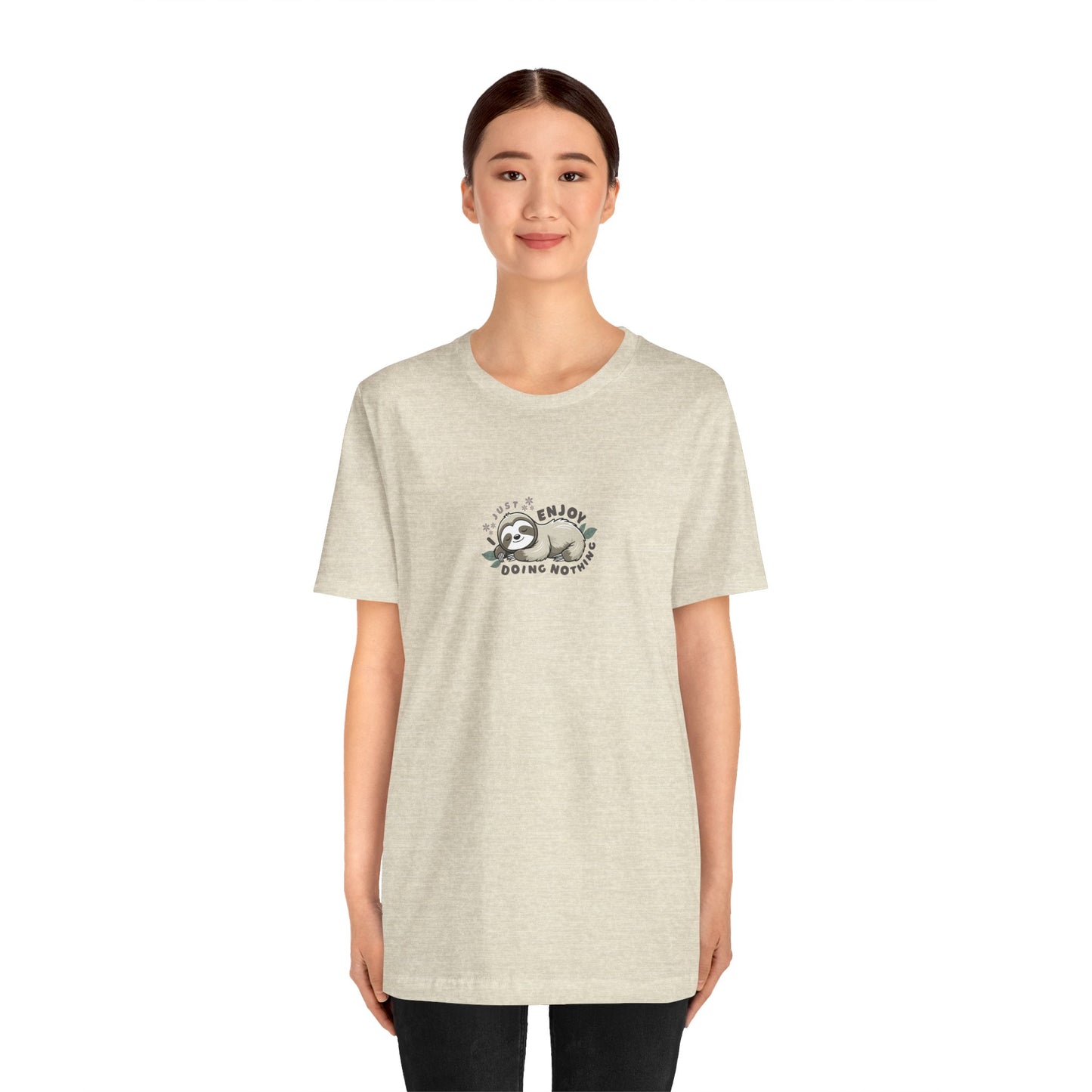 Woman wearing a cream beige t-shirt with a sleeping sloth graphic and text 'I just enjoy doing nothing' on a white background