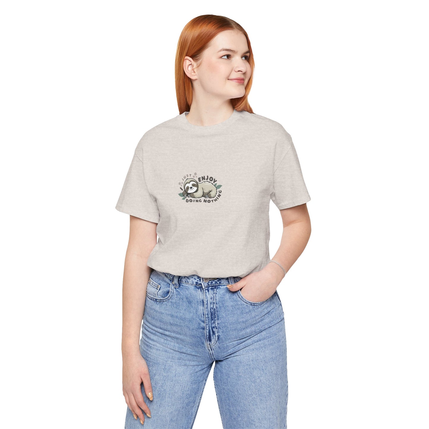 Woman wearing a almond beige t-shirt with a sloth graphic and text 'I just enjoy doing nothing' on a white background
