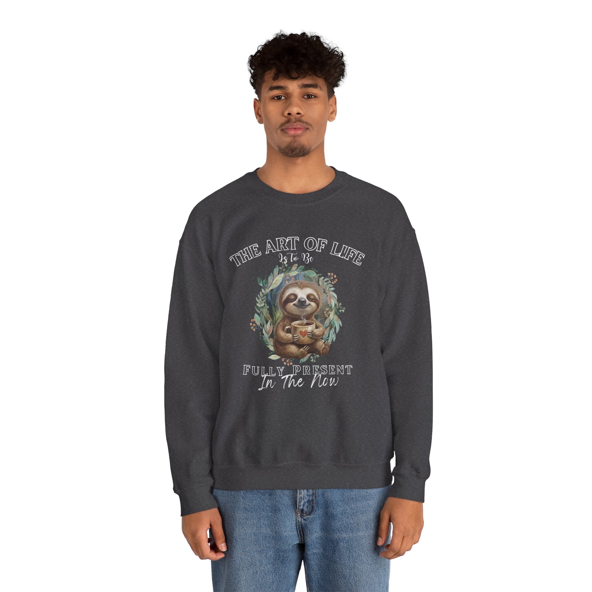 Man wearing a dark gray sweatshirt with a sloth drinking coffee graphic and text 'The art of life is to be fully present in the now' on a white background