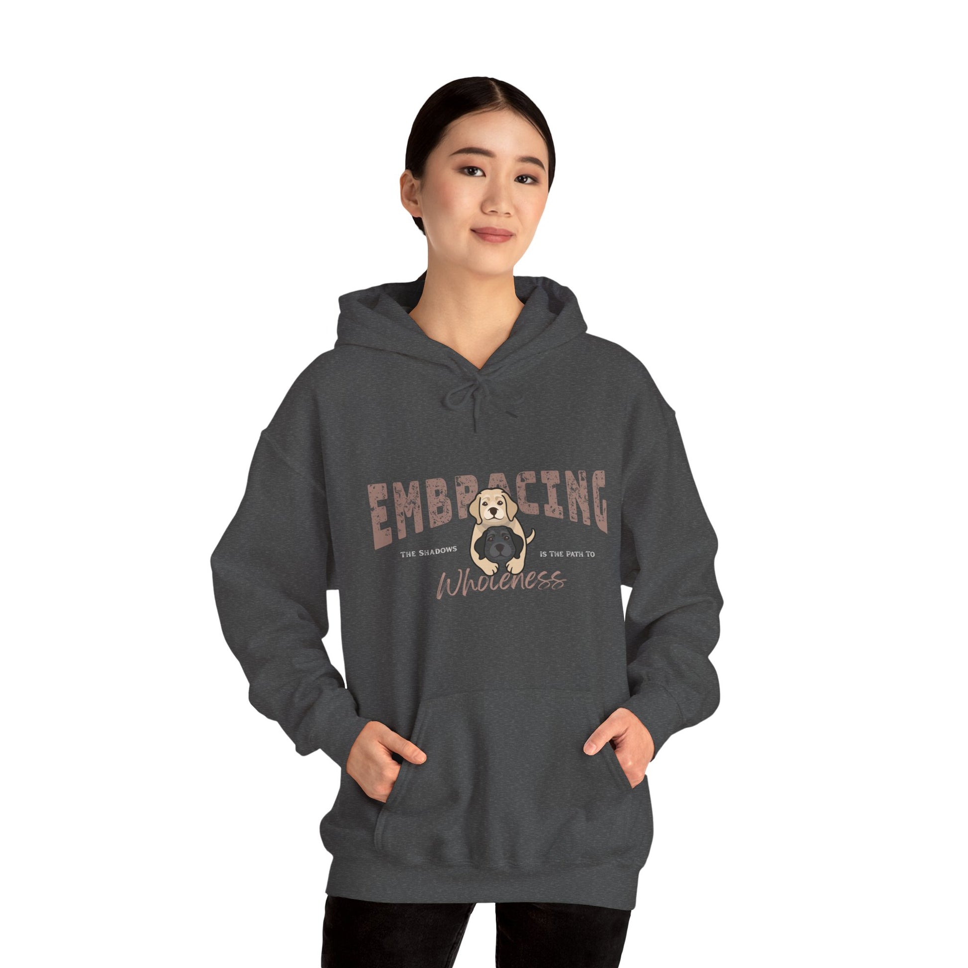 Woman wearing a dark gray hoodie with a graphic of yellow Labrador Retriever hugging black Labrador Retriever and text 'Embracing the shadows in the path to wholeness' on a white background