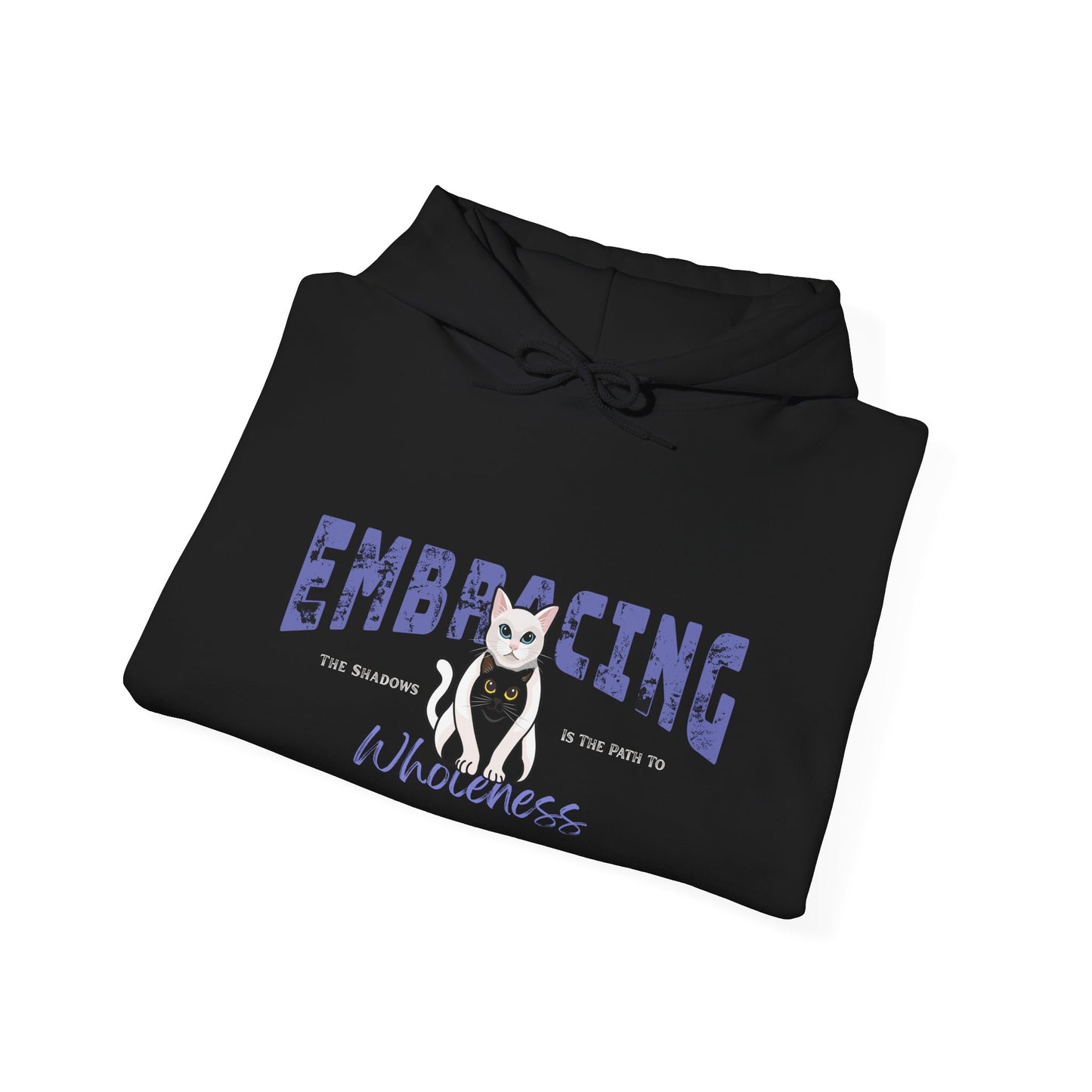 Folded black hoodie with a graphic of white cat hugging black cat and text 'Embracing the shadows is the path to wholeness' on a white background