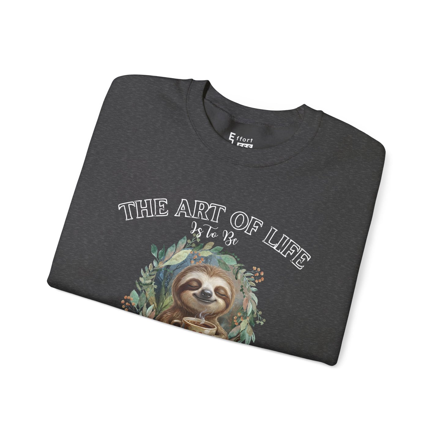 Folded dark gray sweatshirt with a sloth drinking coffee graphic and text 'The art of life' on a white background