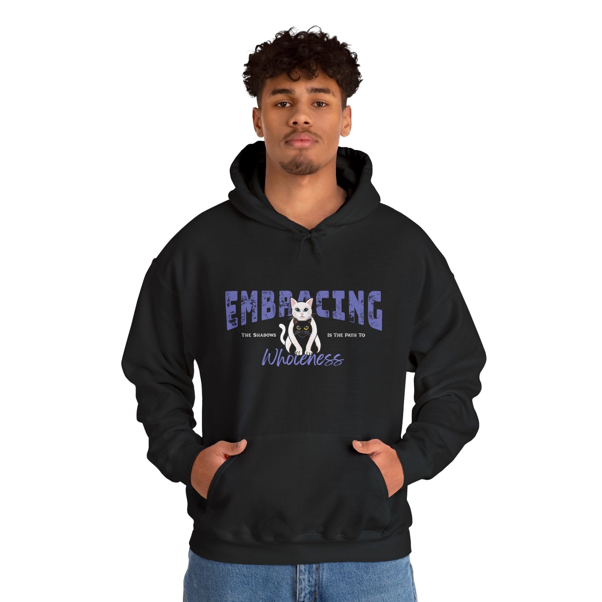 Man wearing a black hoodie with a graphic of white cat hugging black cat and text 'Embracing the shadows is the path to wholeness' on a white background