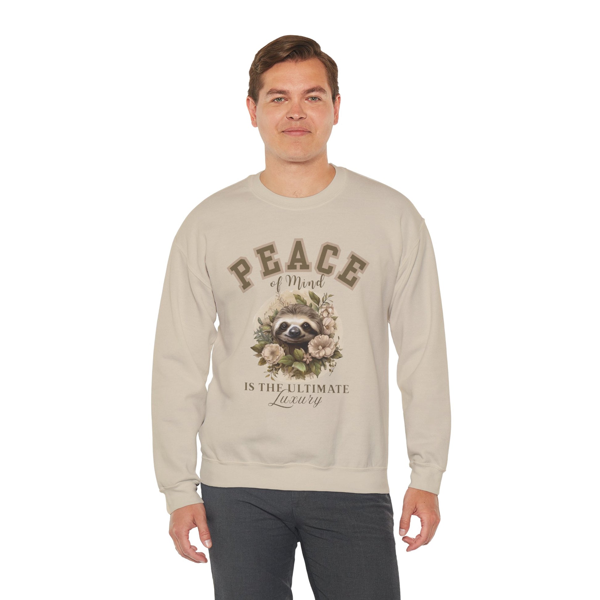 Man wearing a sand beige sweatshirt with a floral sloth graphic and text 'Peace of mind is the ultimate luxury' on a white background