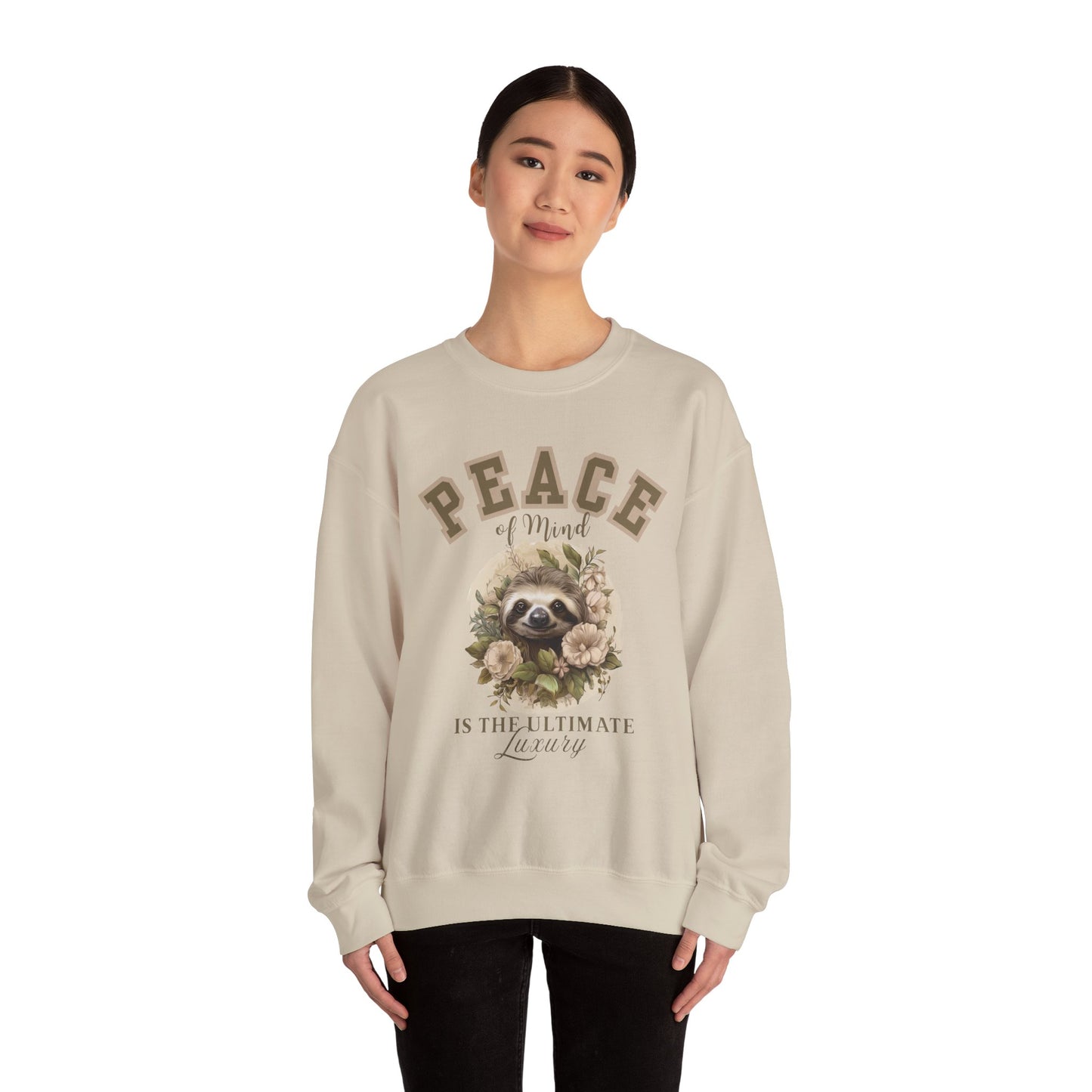 Woman wearing a sand beige sweatshirt with a floral sloth graphic and text 'Peace of mind is the ultimate luxury' on a white background