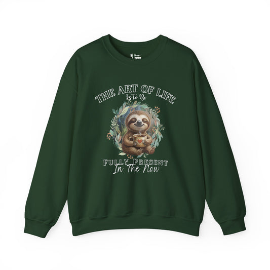 Dark green sweatshirt with a graphic of sloth drinking tea and text 'The art of life is to be fully present in the now' on a white background