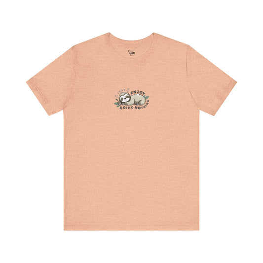 Peach-colored t-shirt with a sleeping sloth graphic and text 'I just enjoy doing nothing' on a white background