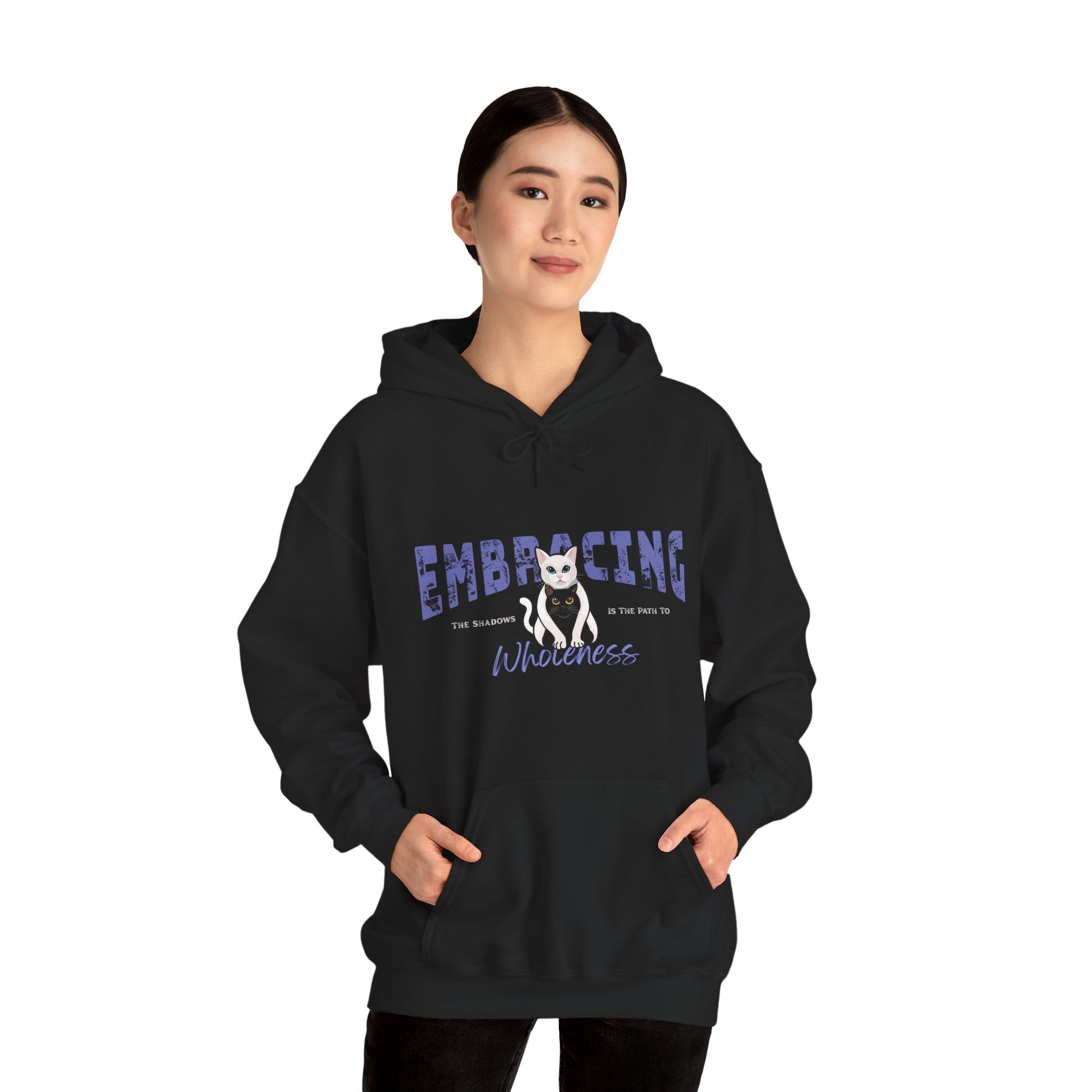 Woman wearing a black hoodie with a graphic of white cat hugging black cat and text 'Embracing the shadows is the path to wholeness' on a white background
